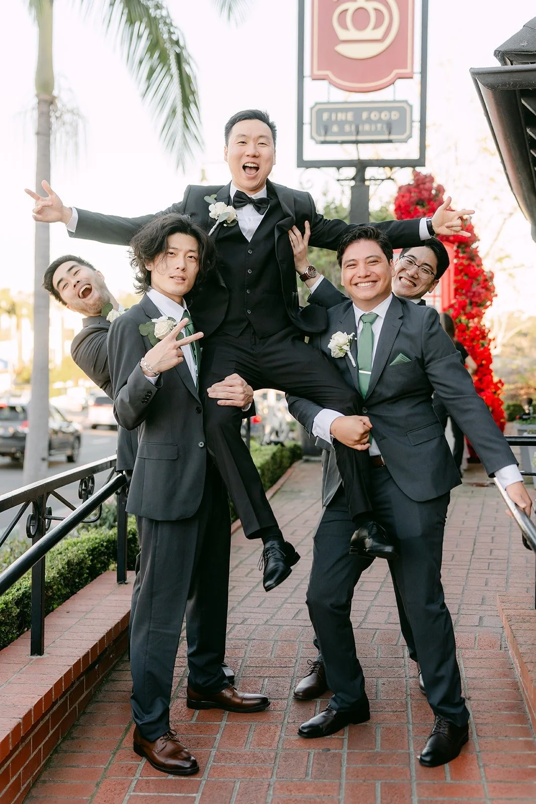 Groomsmen lifting one of the crew in the air beside Jason