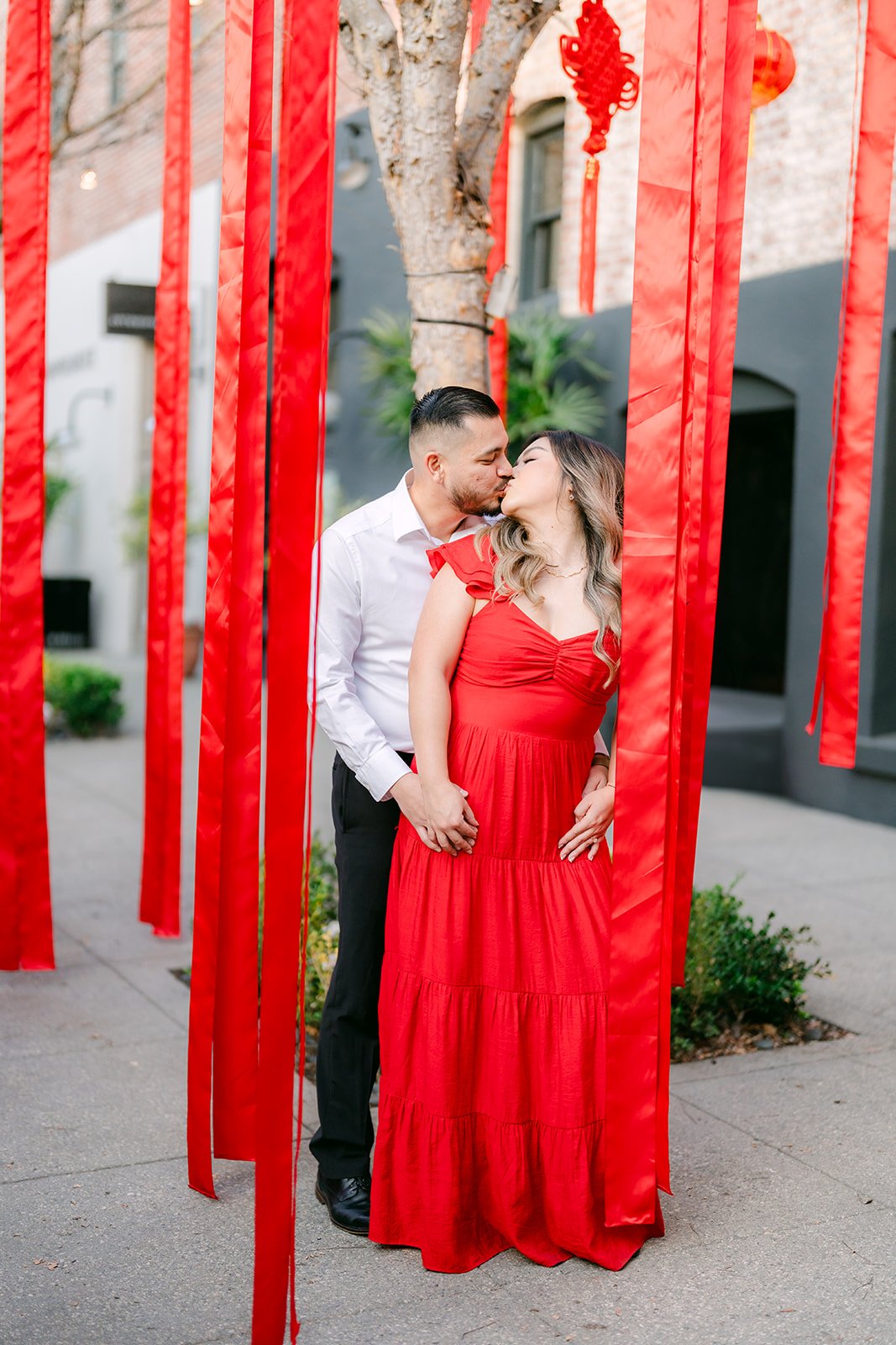 Linh and Ankush embrace between the red streamers.