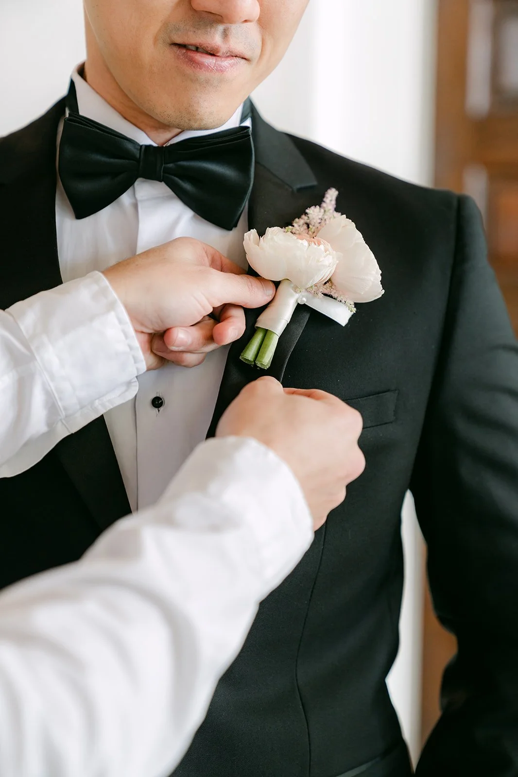 Boutonniere being pinned to the groom's lapel