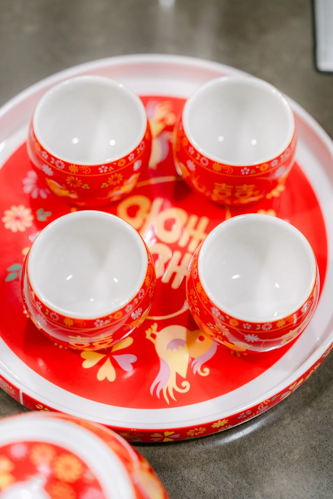Four red double happiness teacups on a round red tray.