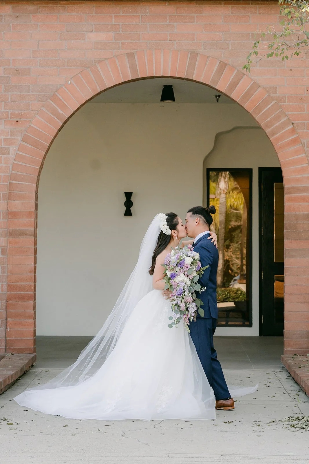 Kate and Michael embracing under a brick archway.
