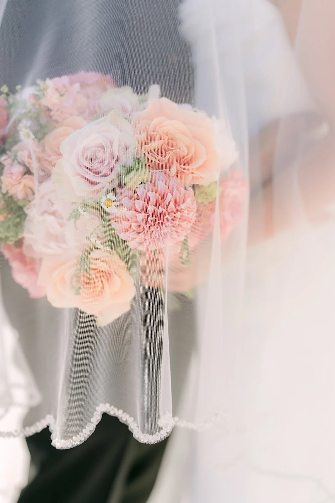 A soft close view of Stephanie's bouquet through her veil