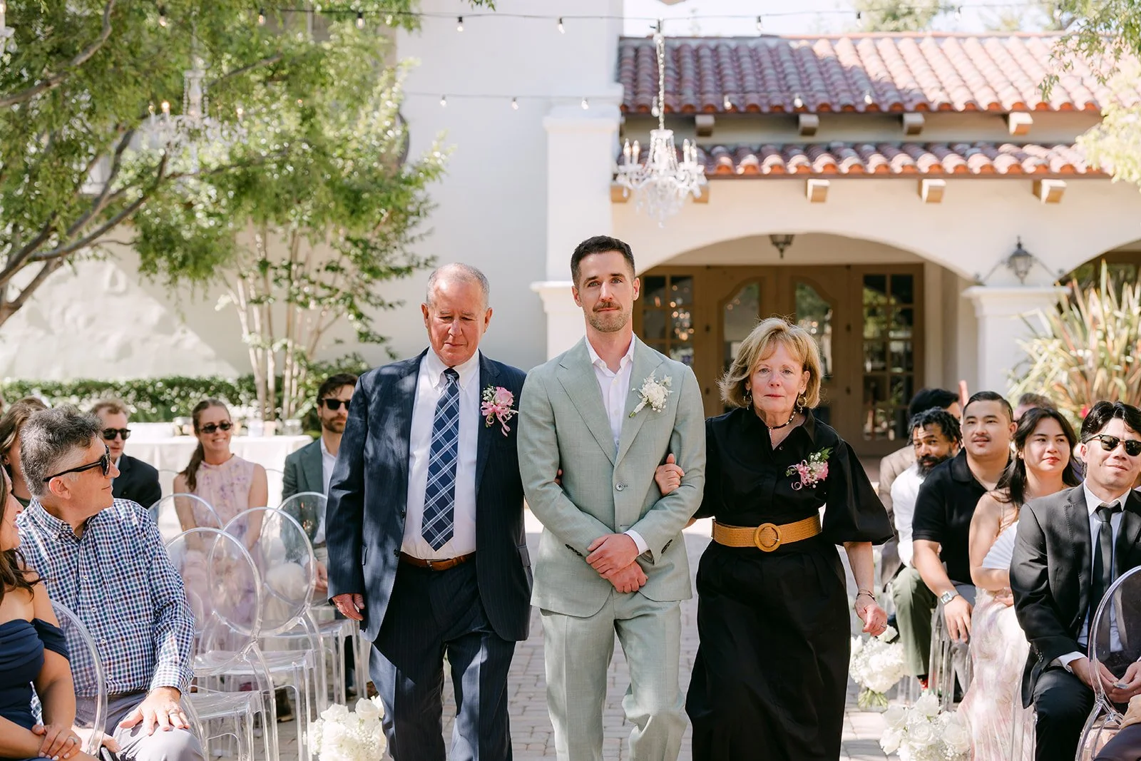 Groom walking down the aisle with his parents