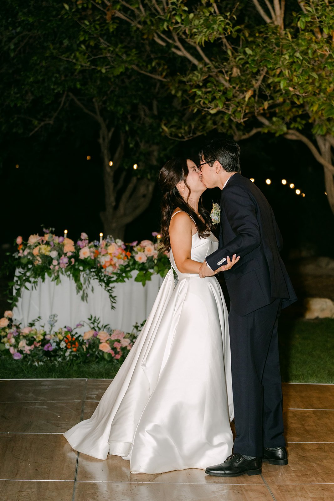 A kiss on the dance floor by the sweetheart table