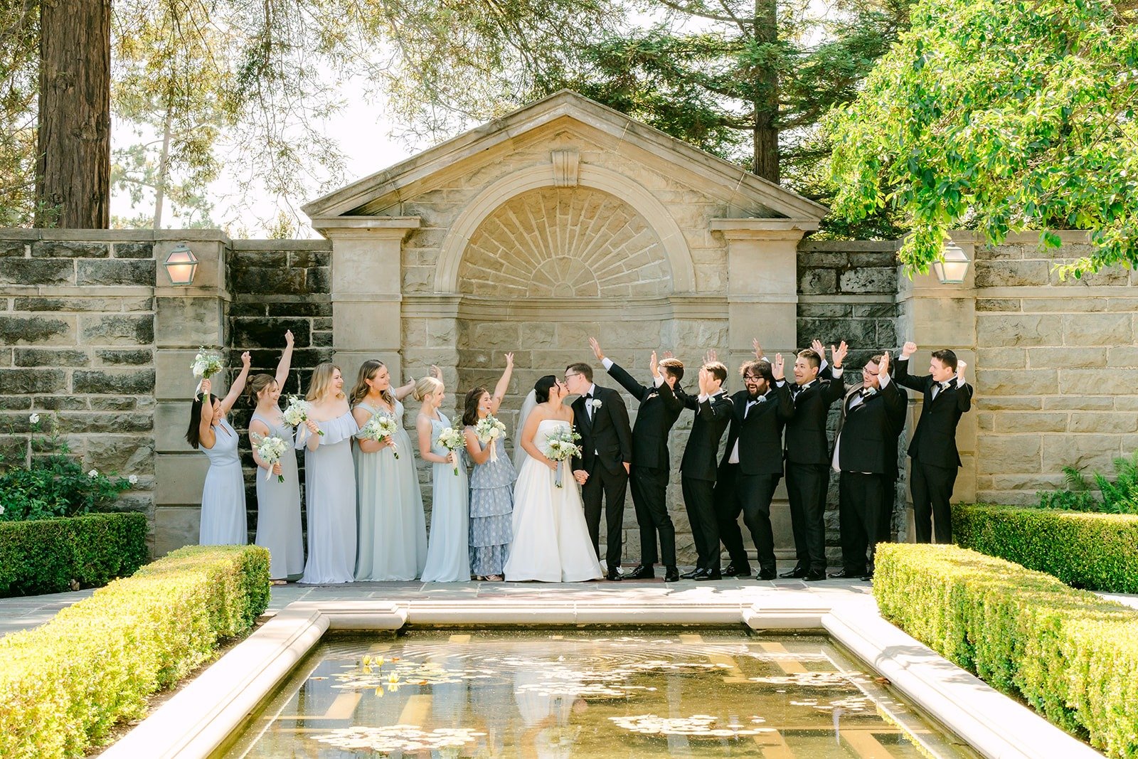 Full wedding party lined up beside the reflecting pool
