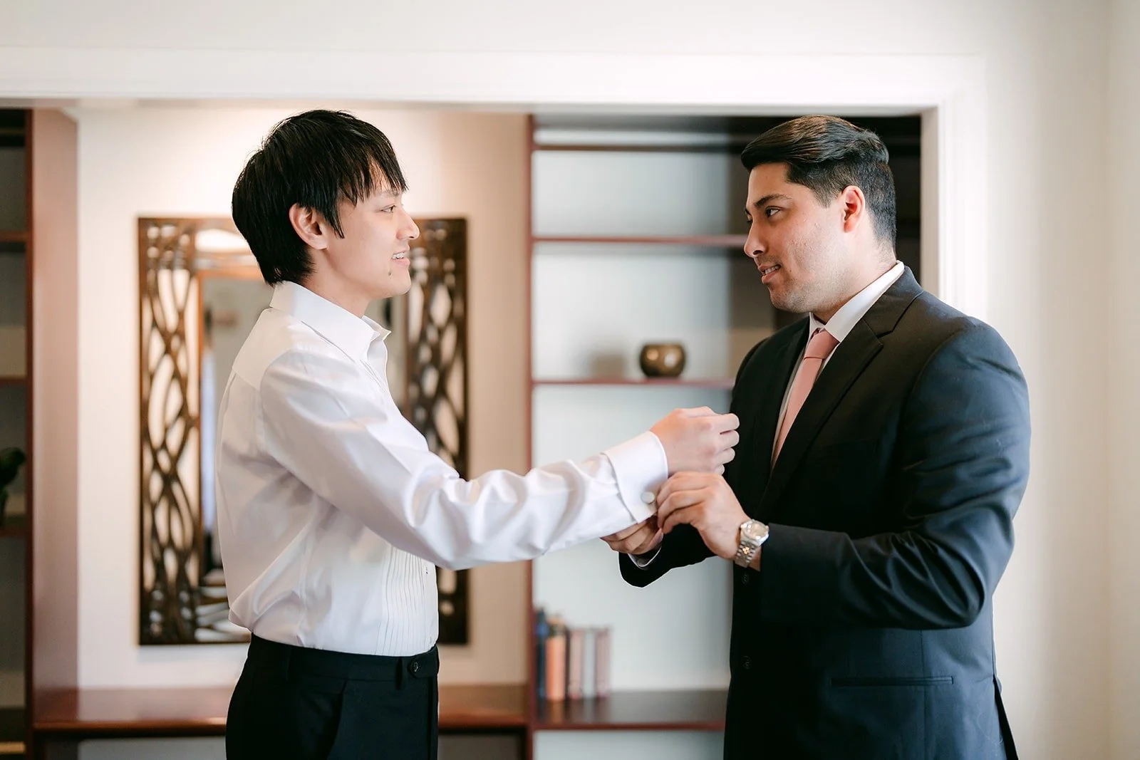 A groomsman helping Job with his cufflinks