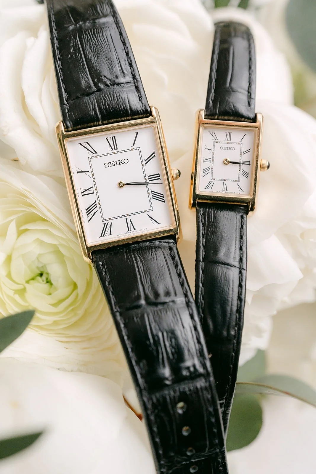 His and hers black leather watches on white roses