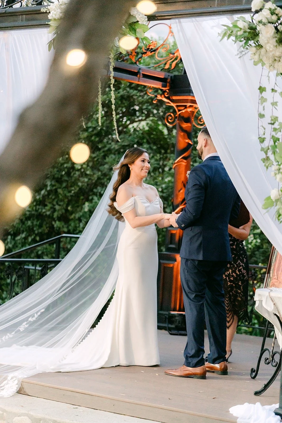 Mariana and Danny facing each other under the gazebo with string lights glowing