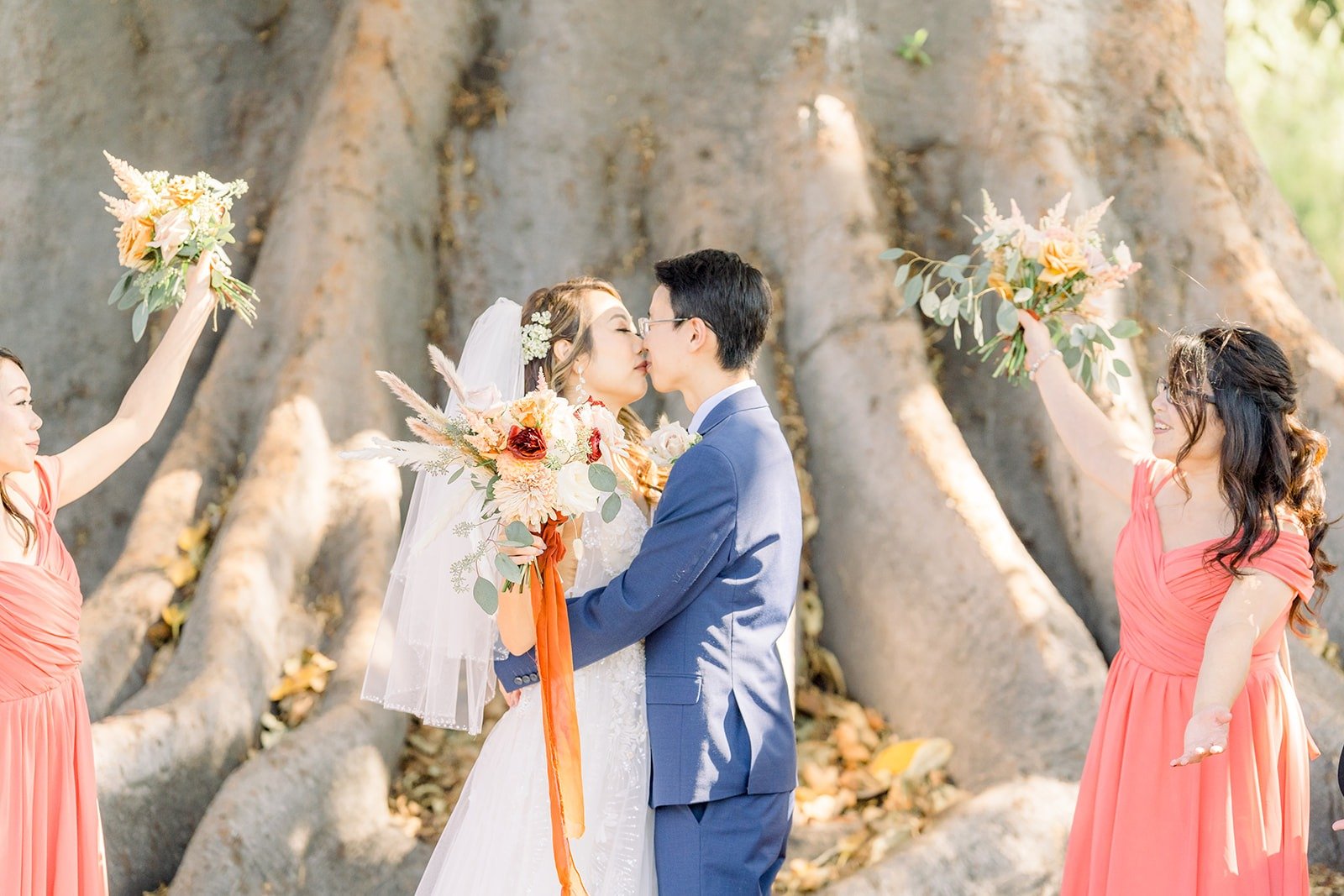 Ariel and Alex with their bouquets raised by the wedding party