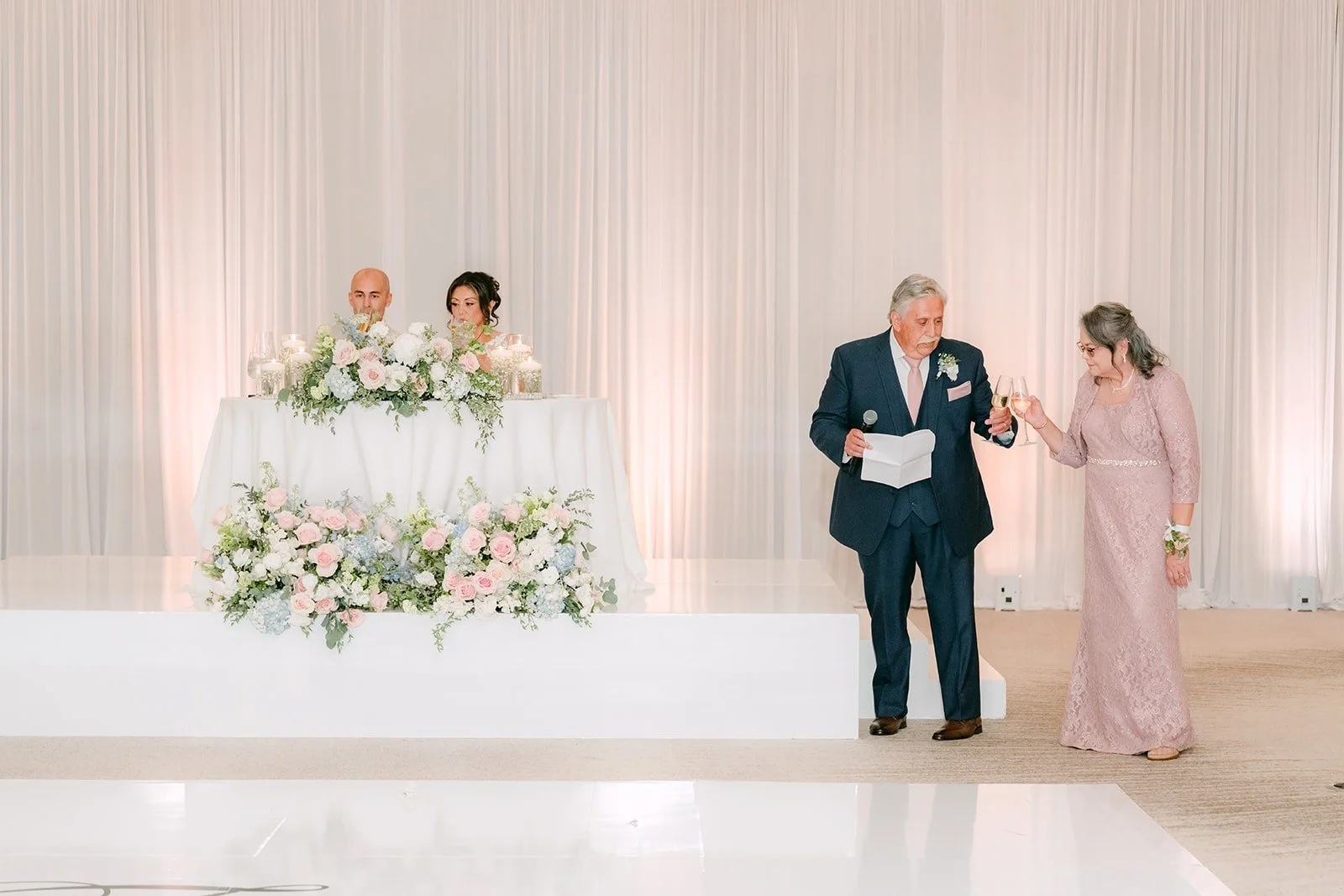 A couple gives a speech in front of the sweetheart table