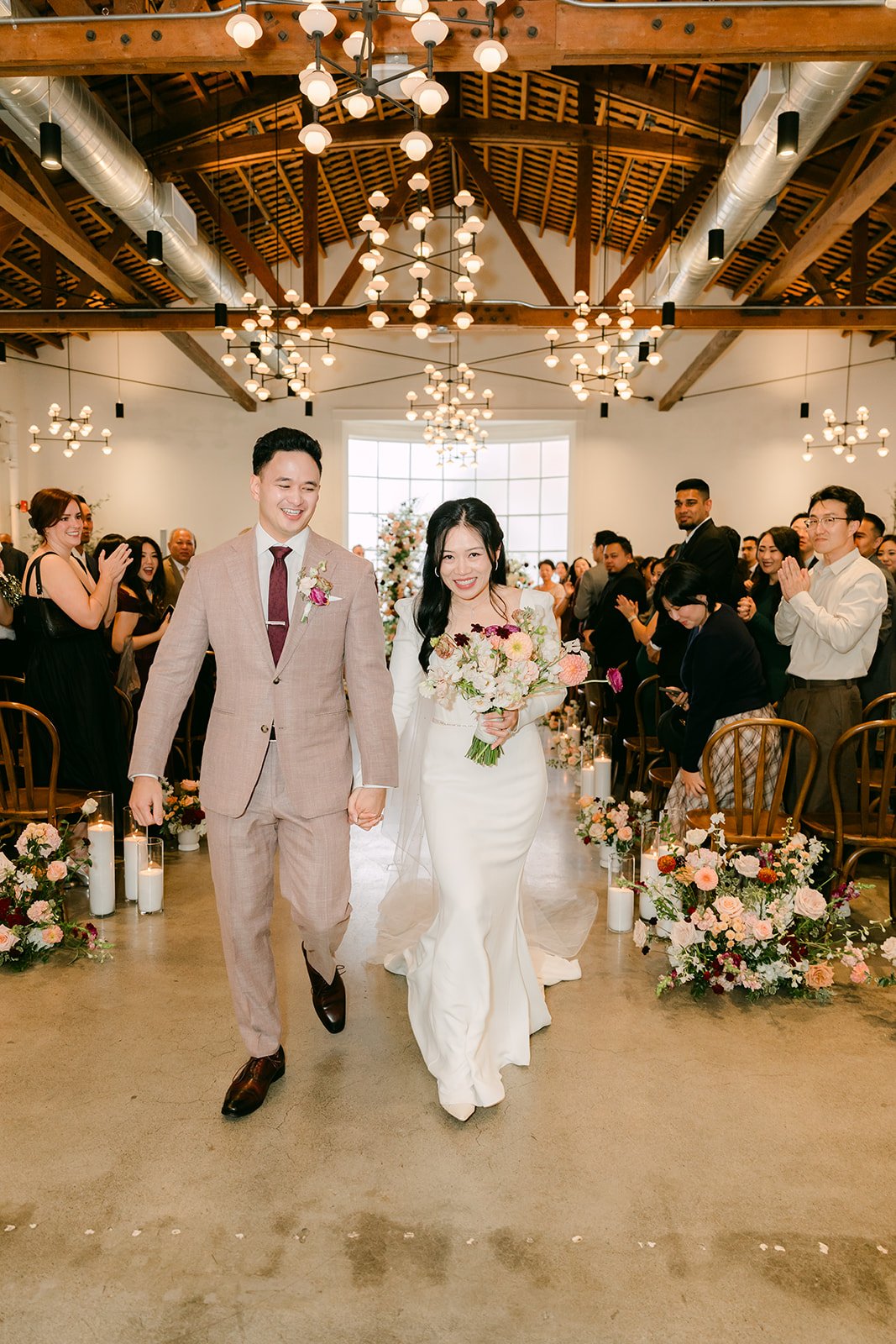Denise and Michael walking back up the aisle as guests cheer.