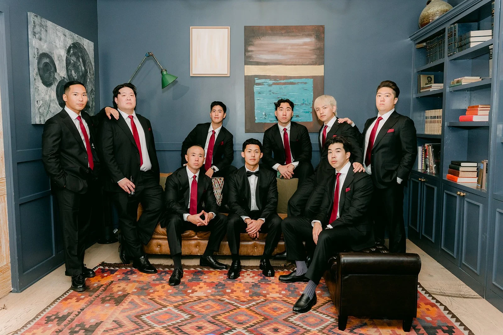 Groomsmen in black tuxedos and red ties in the library suite at The Harper