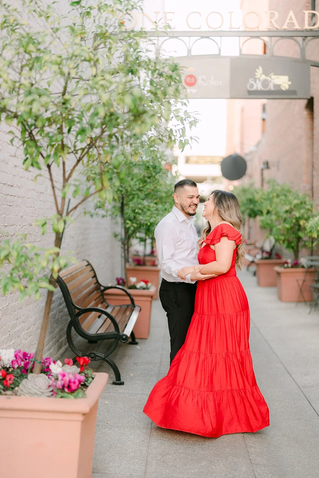 Linh and Ankush embracing in the paseo among potted trees.
