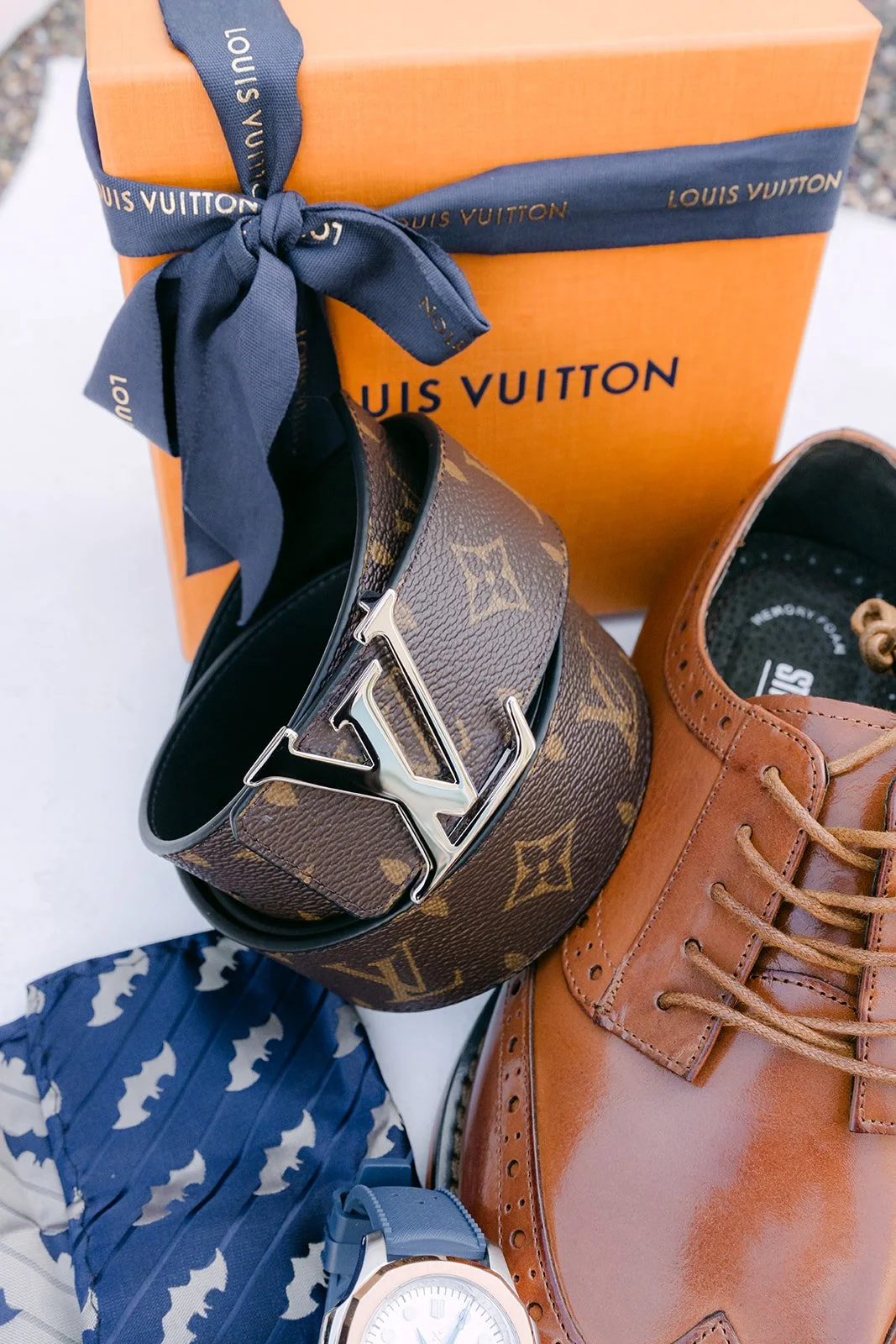 Michael's watch, belt and shoes with a gift tied in navy ribbon.