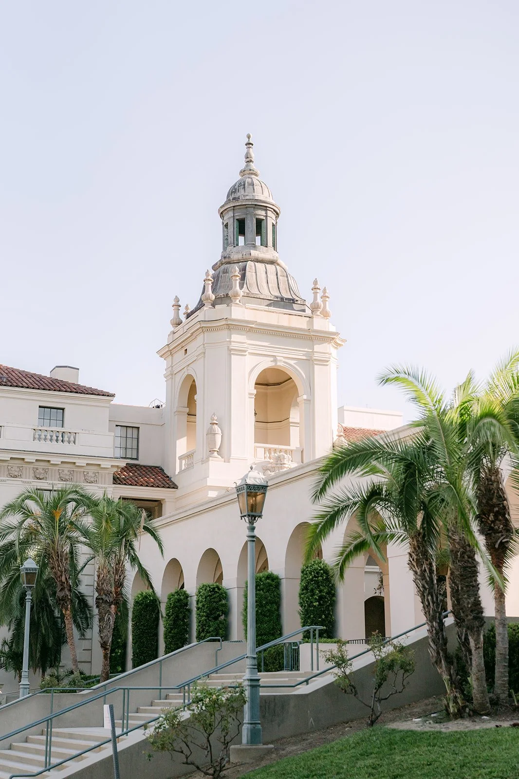 The bell tower of Pasadena City Hall framed by palm trees and blue sky.