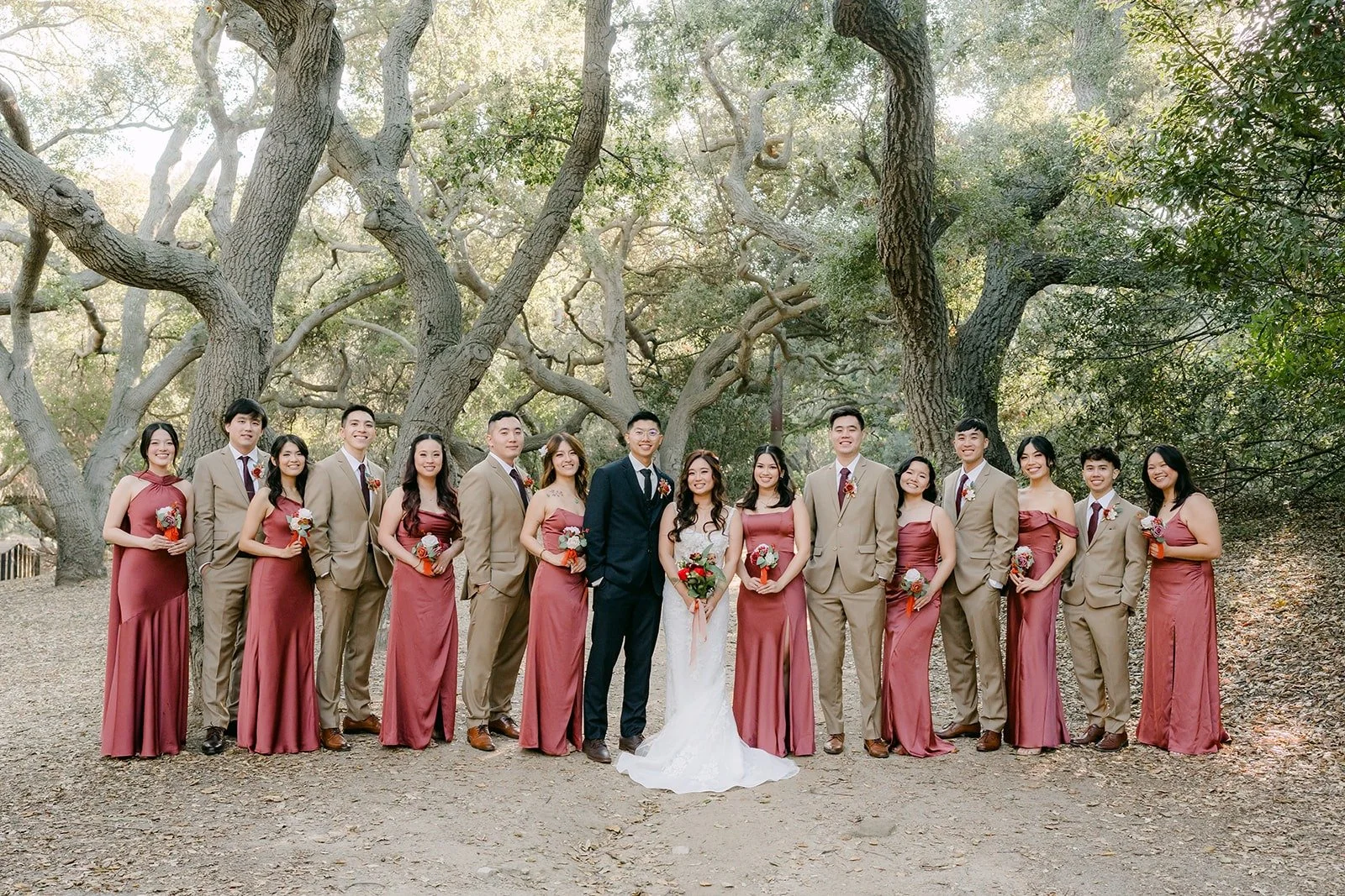The full wedding party lined up beneath the oak canopy at Oak Canyon Nature Center