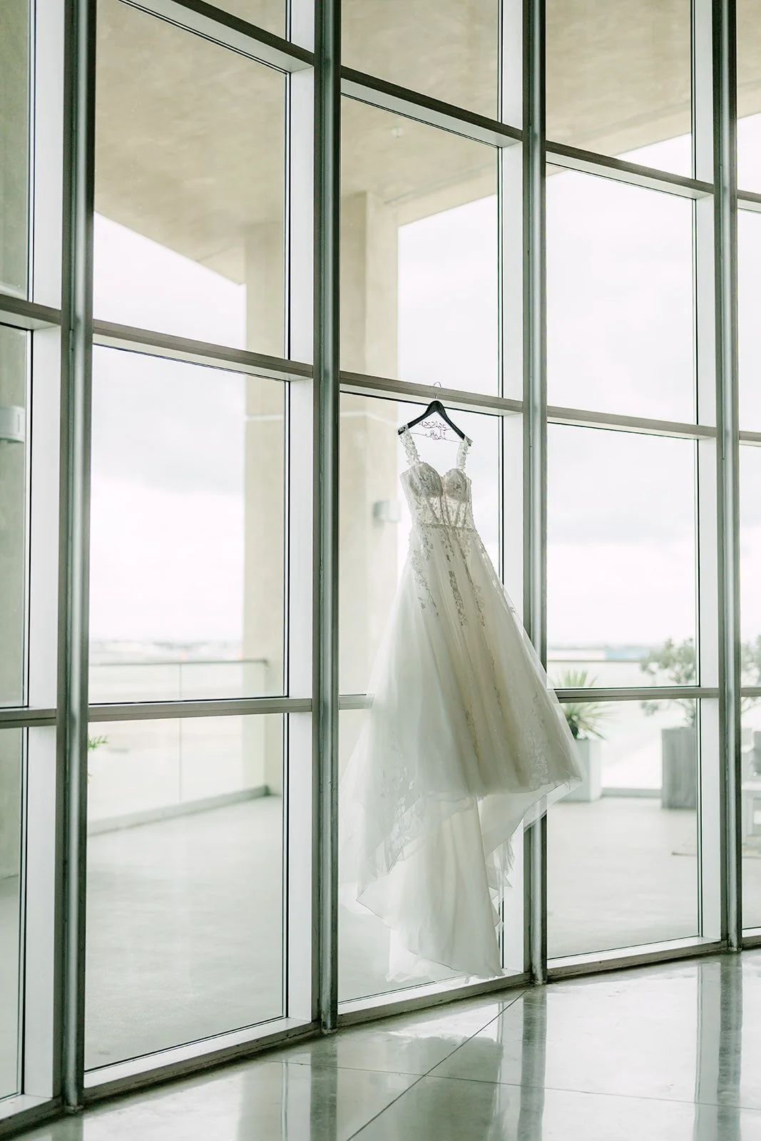 Wedding gown hanging in the tall windows of the bridal suite at The Modern
