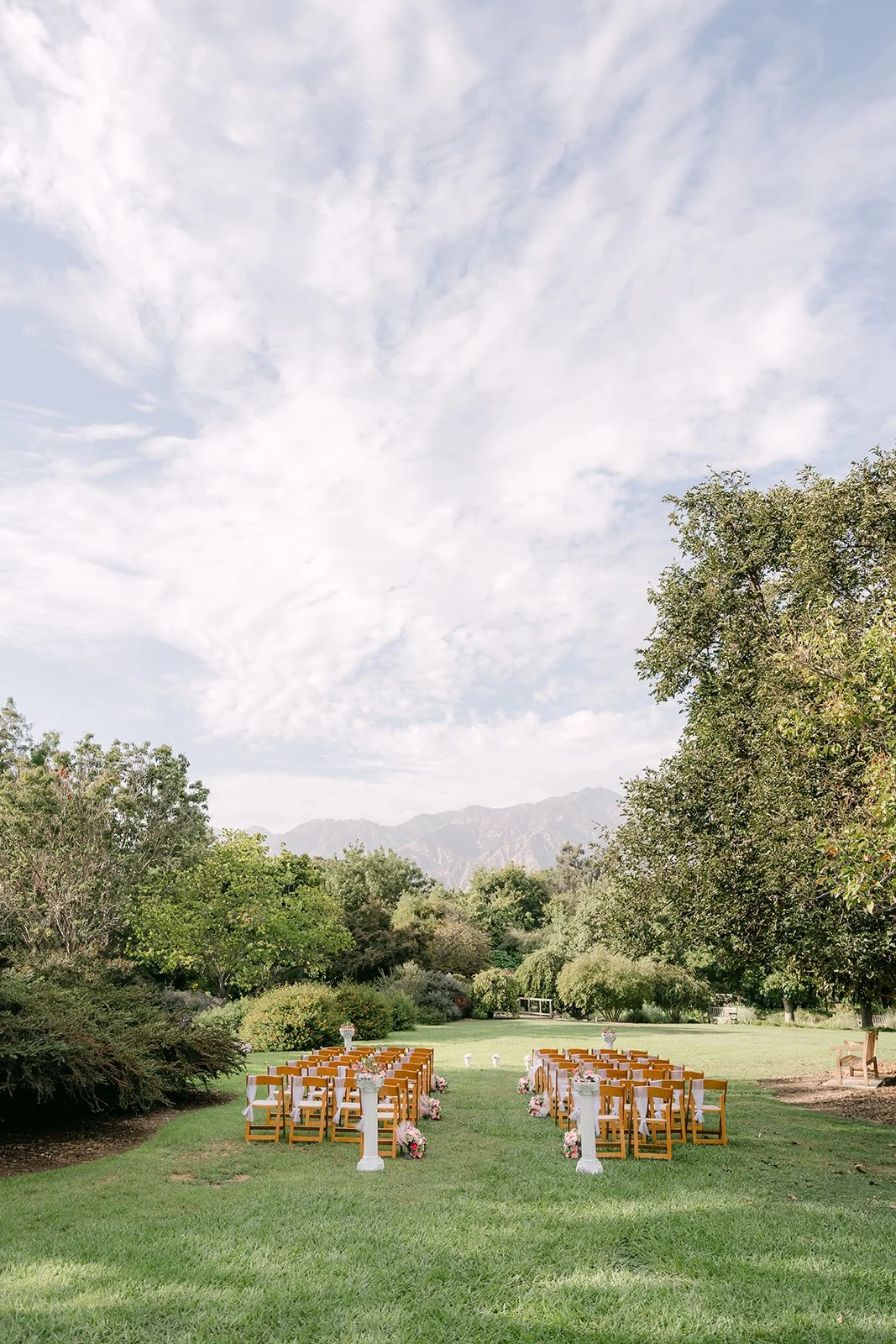 The ceremony lawn with wooden chairs, clouds and the mountains.