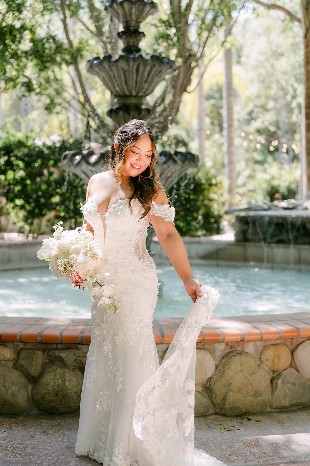 Nicole holding her bouquet by the fountain at Eden Gardens.