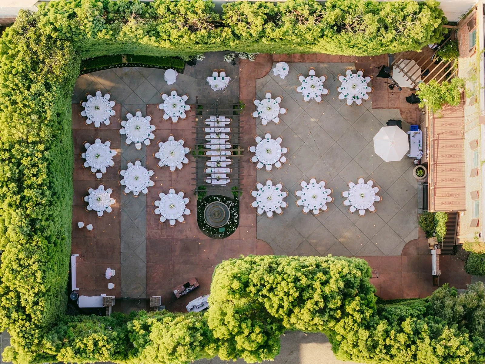 An aerial view of the reception courtyard at Franciscan Gardens with round tables framed by green hedges