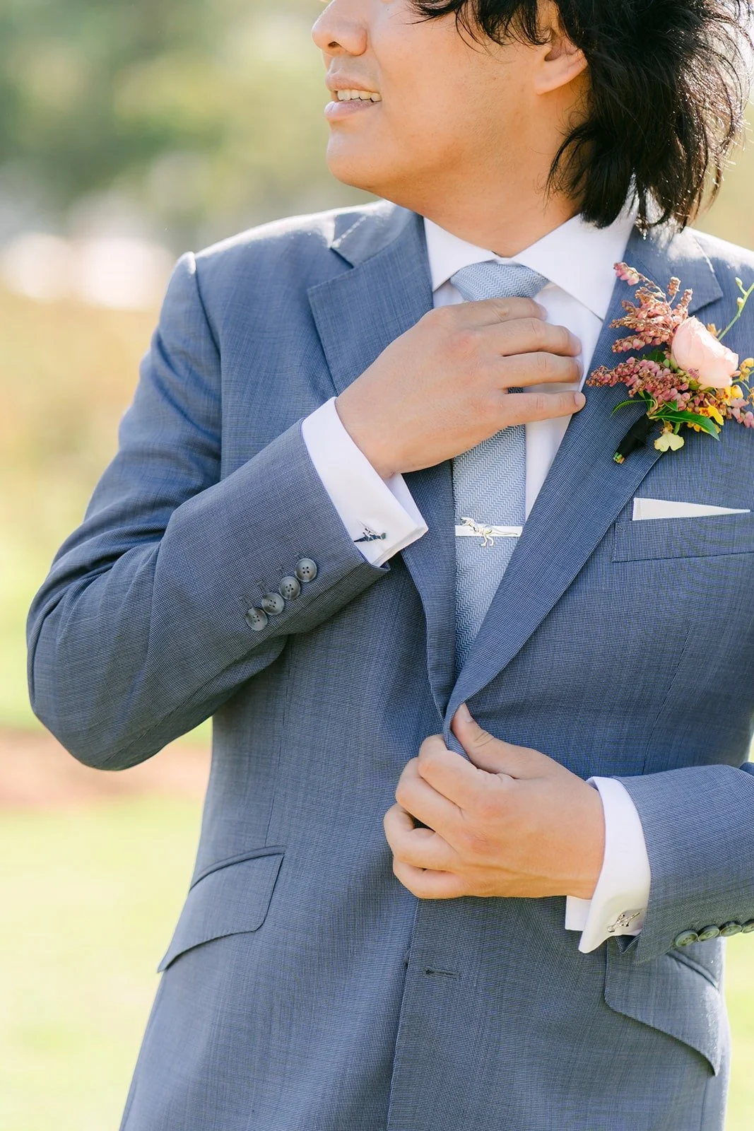 Philip adjusting his jacket with a peach boutonniere