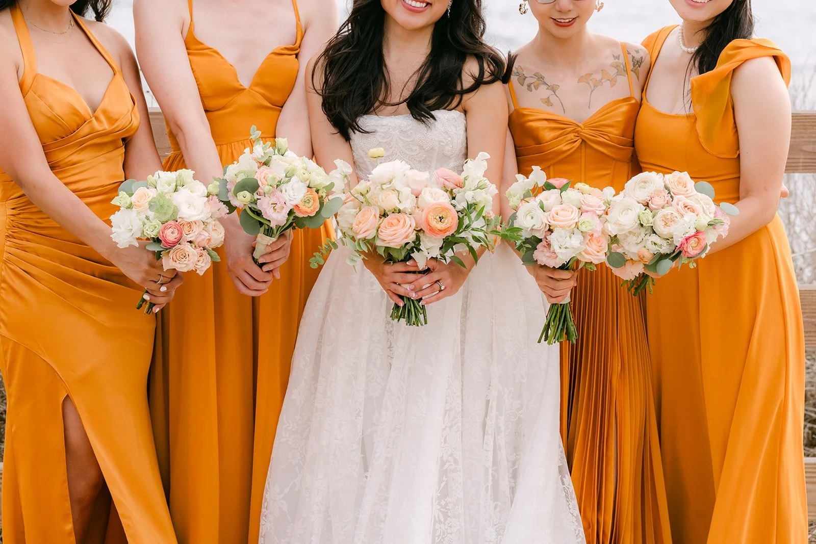Kim with her bridesmaids in marigold gowns holding peach bouquets