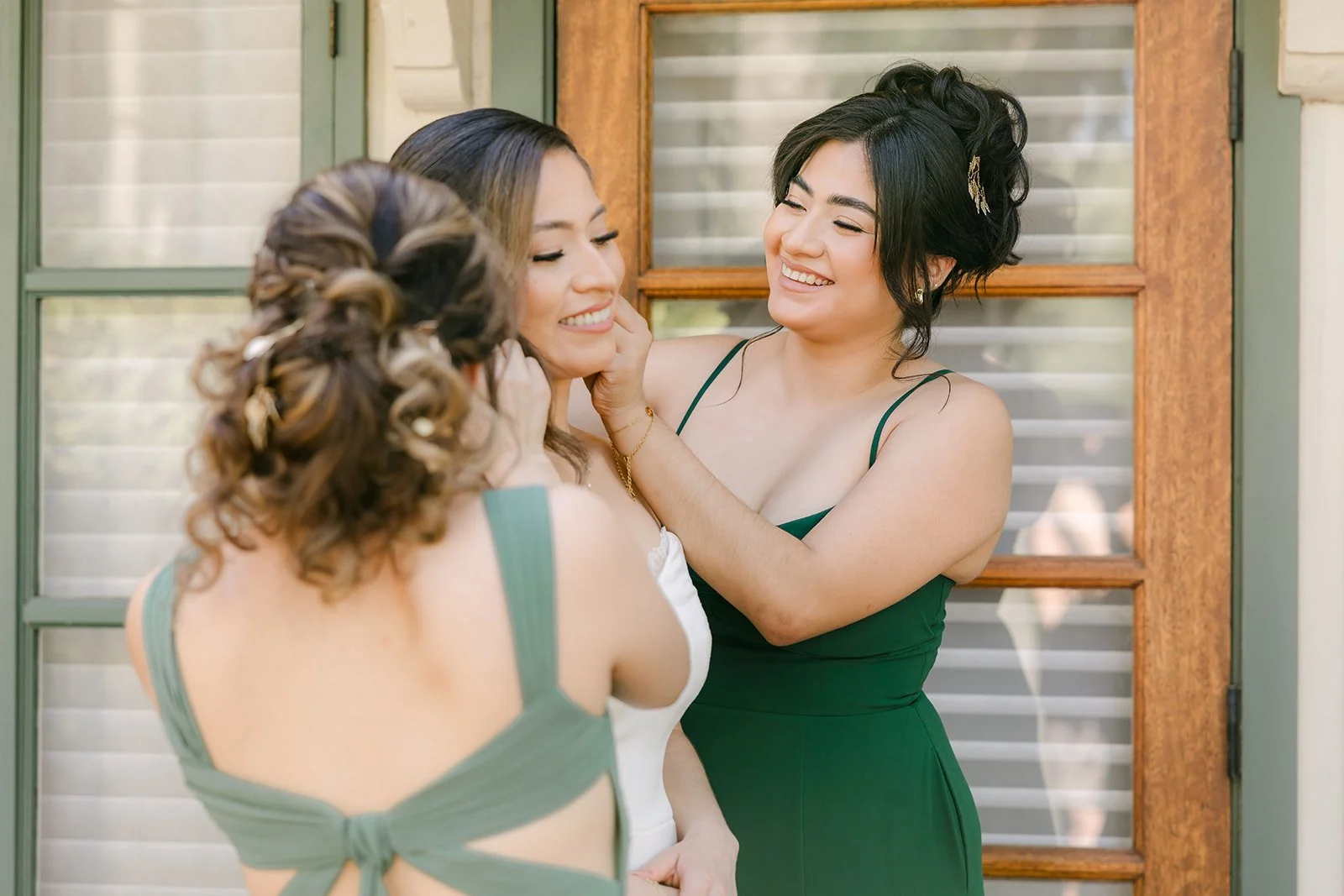 A bridesmaid fastening Mariana's earring in front of the suite windows
