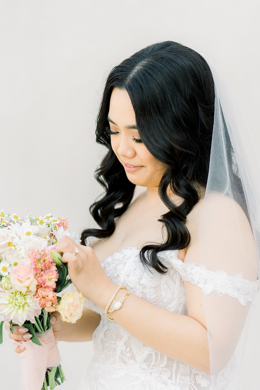 Francesca looking down at her bouquet of pink and peach roses