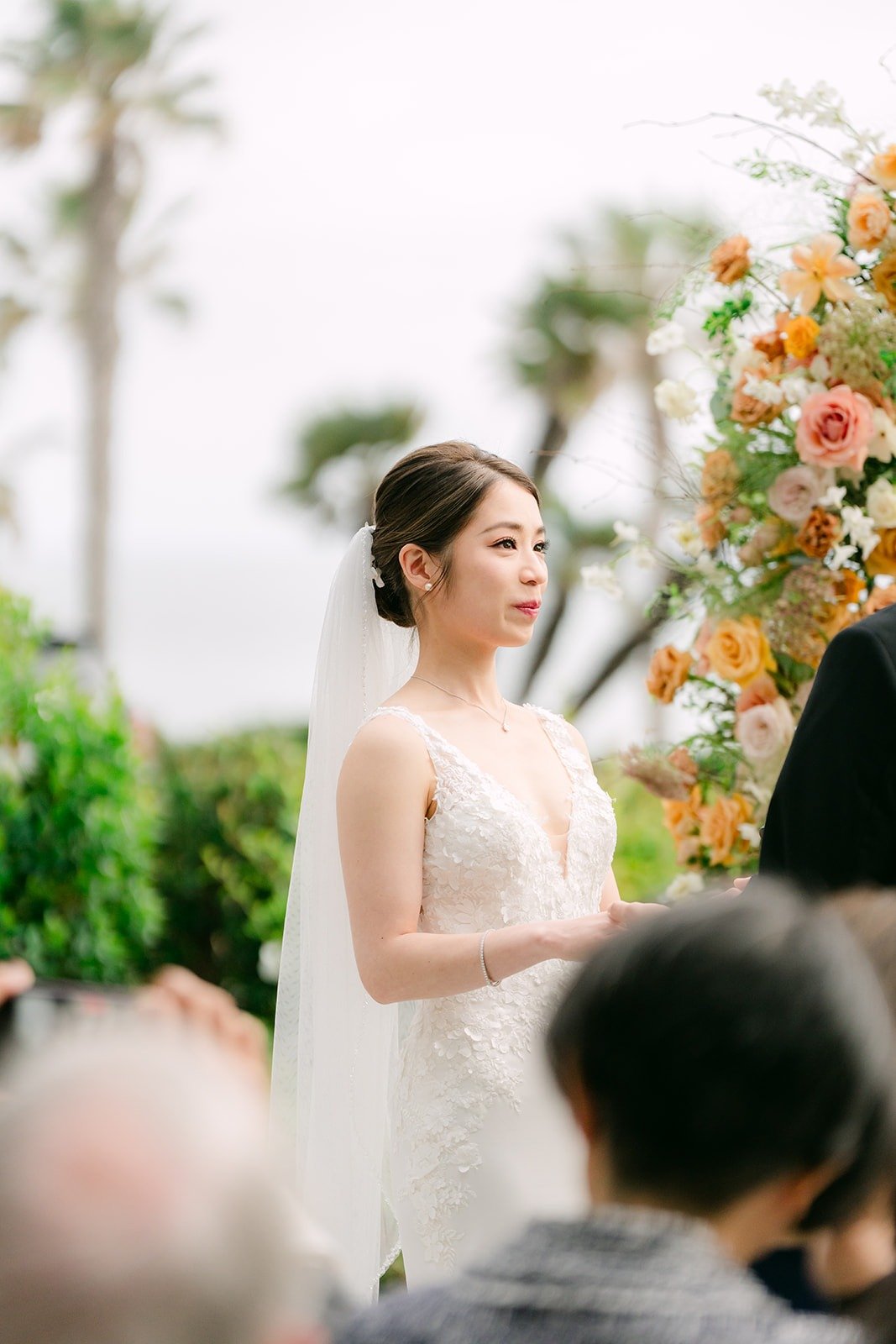 Angela at the front of the aisle in her veil, framed by florals
