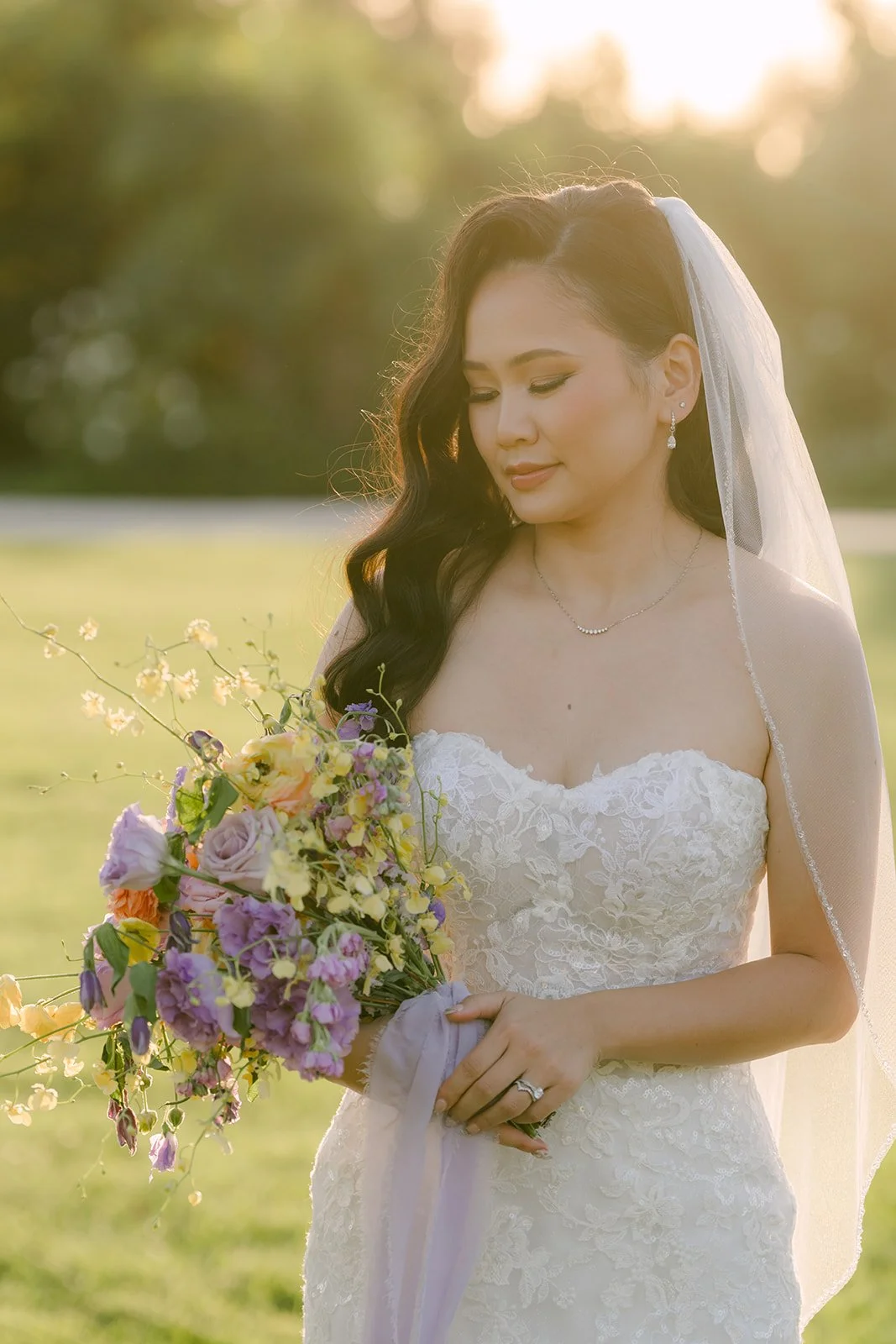Vannie looking down at her bouquet at golden hour.