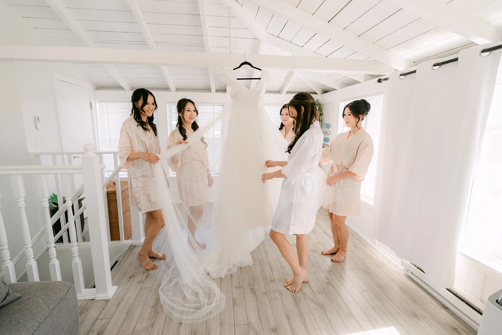 Jadee and her bridesmaids gathered around the wedding gown, photographed by One and Only Production