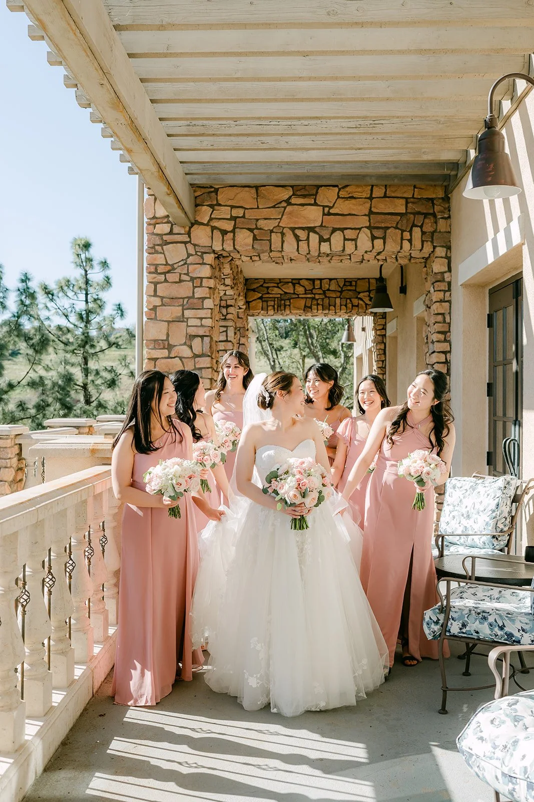 Bride and bridesmaids laughing together on the covered terrace
