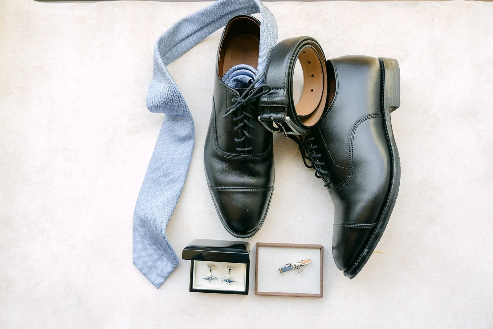 Philip's black dress shoes, light blue tie and cufflinks laid out