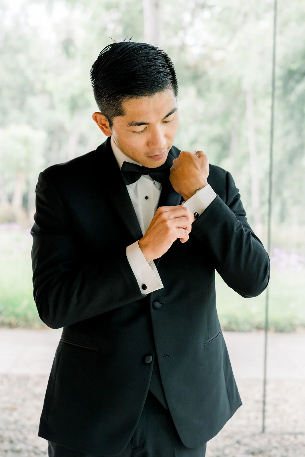 Steven fastens his cufflinks in his black tuxedo