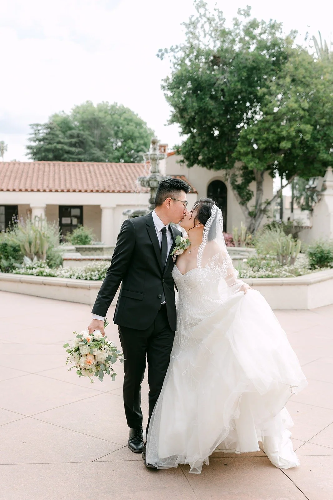 Eunice and Eric walk together across the plaza at San Gabriel Mission, photographed by One and Only Production