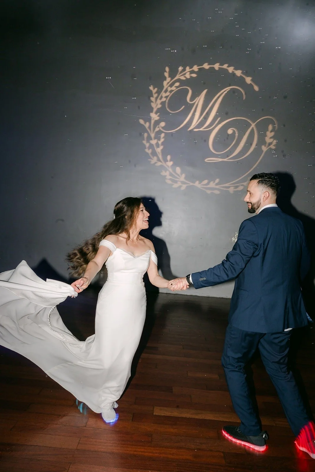 Mariana and Danny dancing in front of their glowing monogram, photographed by One and Only Production