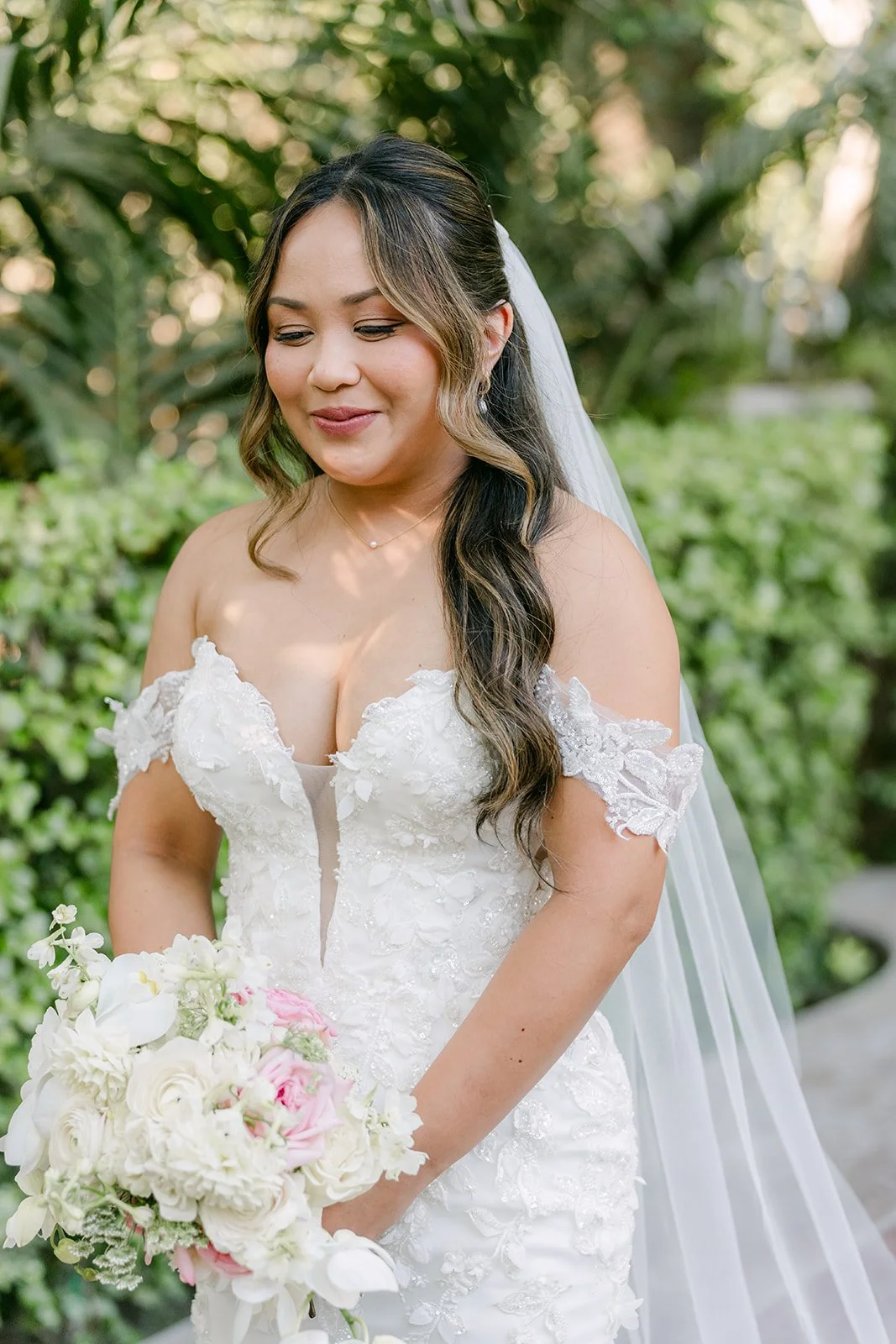 Nicole smiling under her veil as she walks down the aisle at Eden Gardens.