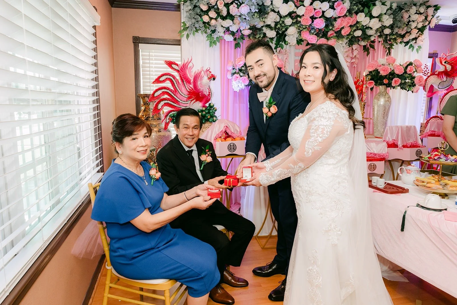 Amy and James serving tea to family seated at the floral backdrop