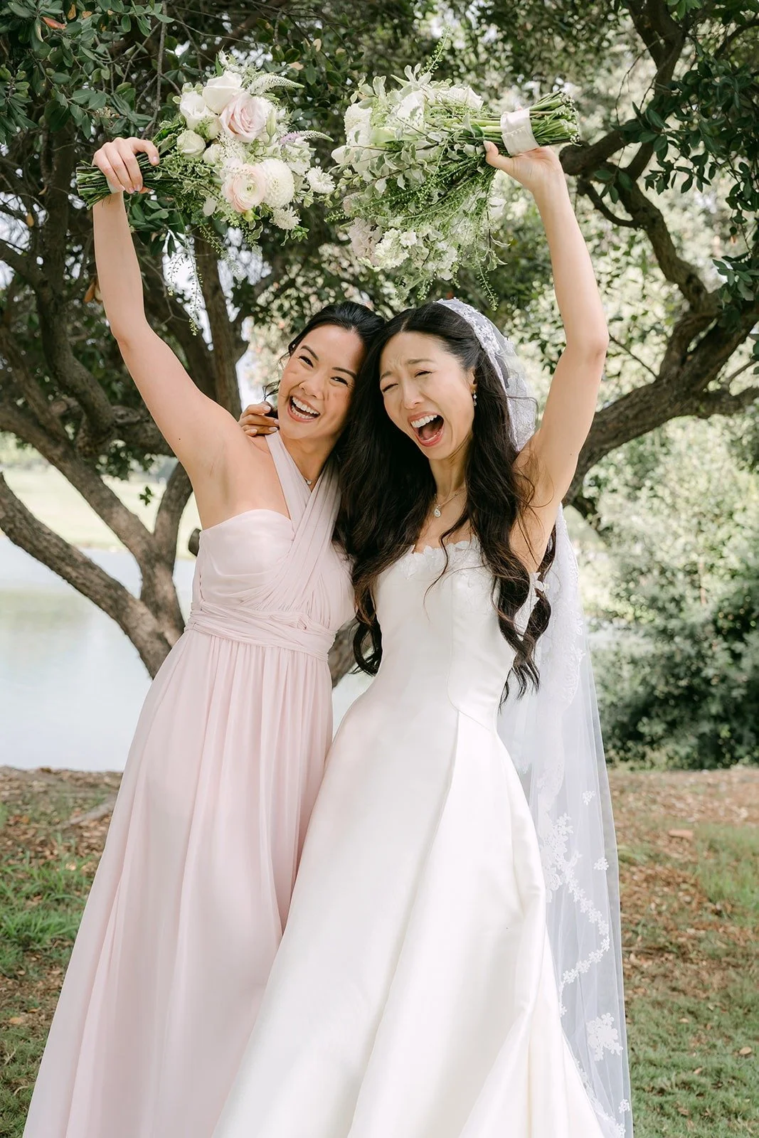 Kristine and a bridesmaid cheering with their bouquets raised