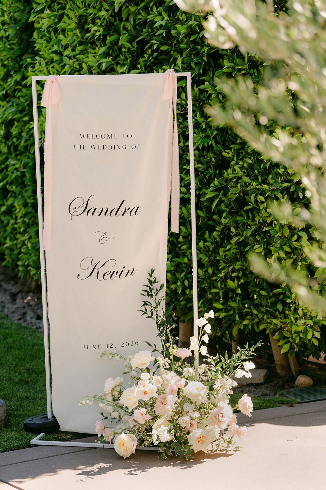 Ceremony welcome banner with Sandra and Kevin's names beside cream florals.