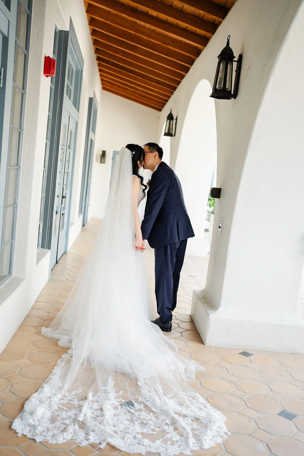 Couple kissing in the arched walkway with the long train behind