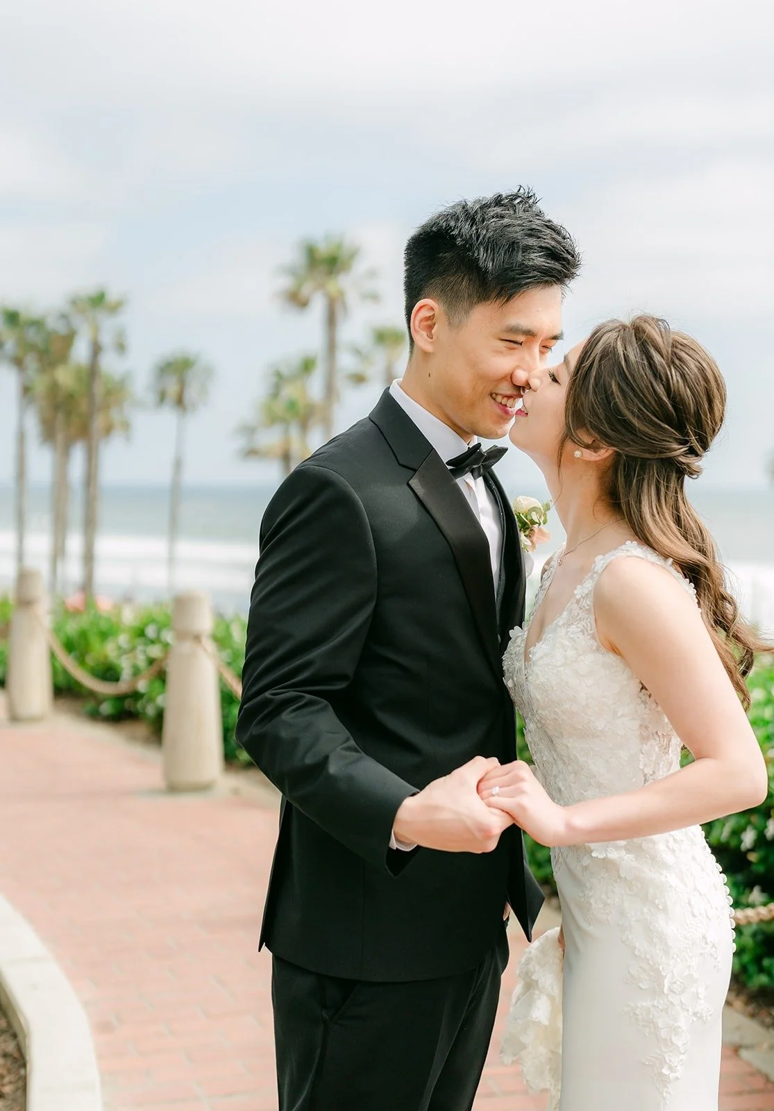 Angela and Eli forehead to forehead with the ocean behind them