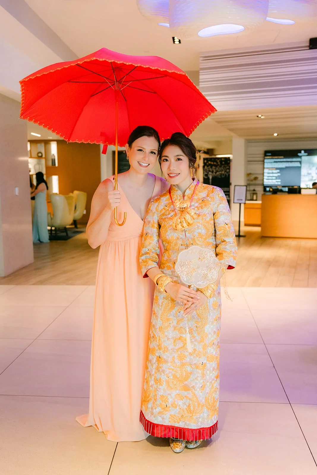 Christie and Christian under a red umbrella in the lobby of the Renaissance Newport Beach Hotel, photographed by One and Only Production.