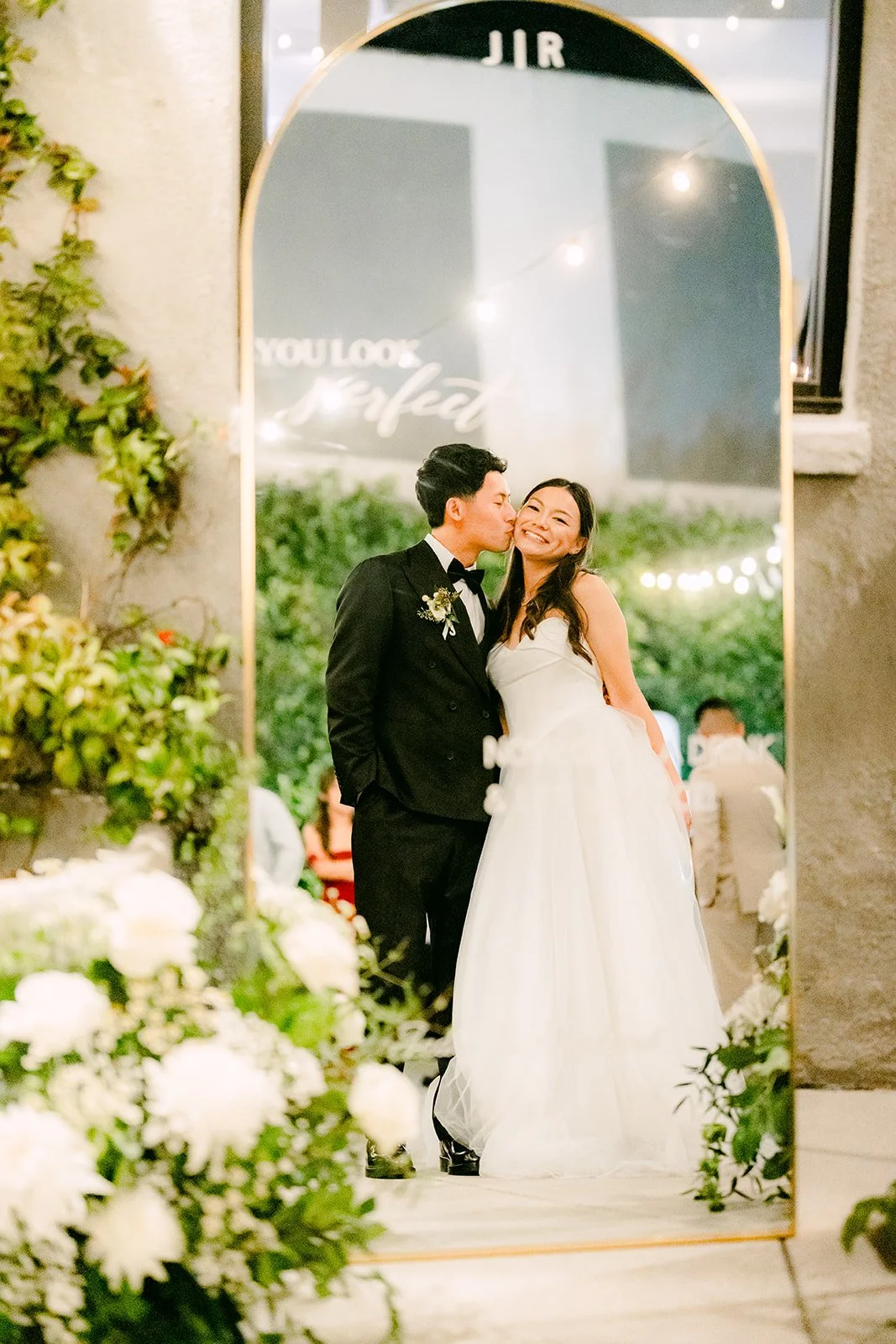 Jadee and Richard kissing in a doorway framed by greenery