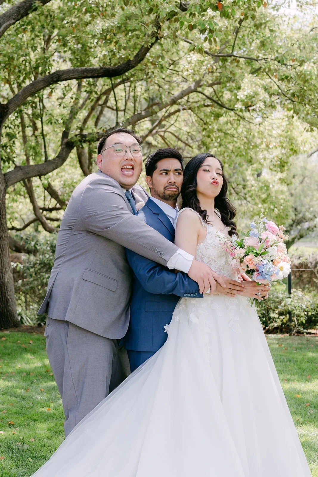 A groomsman giving Mark and Natalie a big hug on the lawn