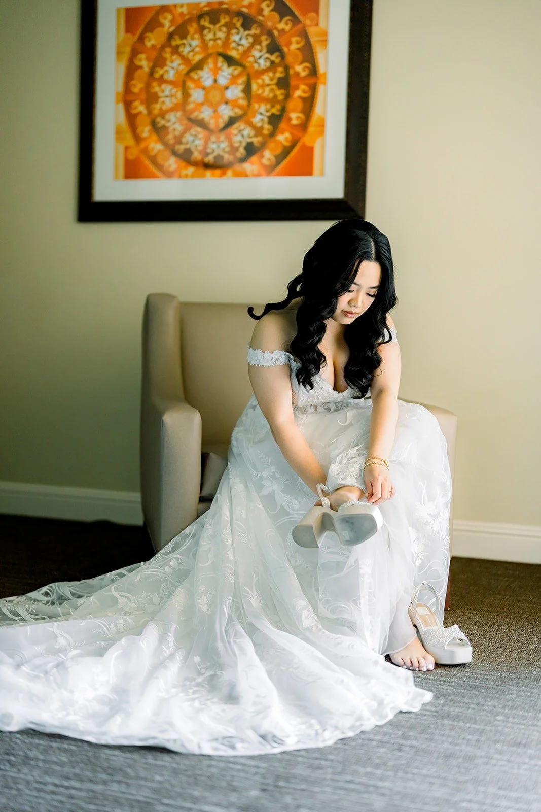 Francesca sitting in an armchair as she puts on her wedding shoes