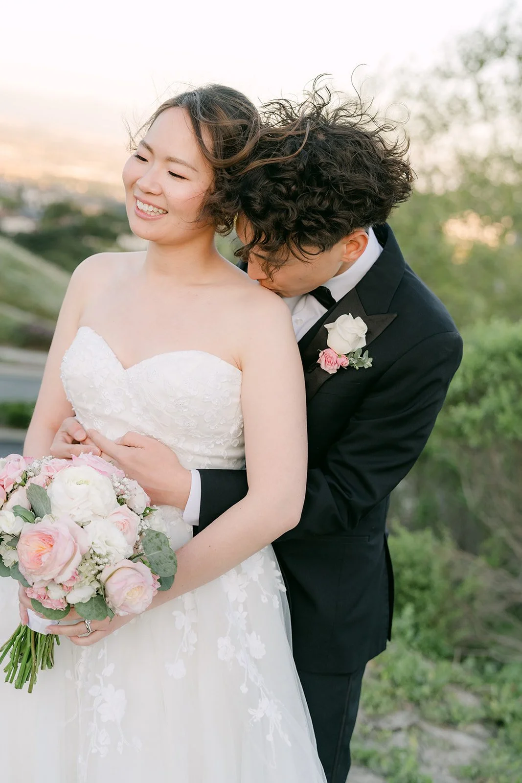 Groom kissing the bride's shoulder at sunset