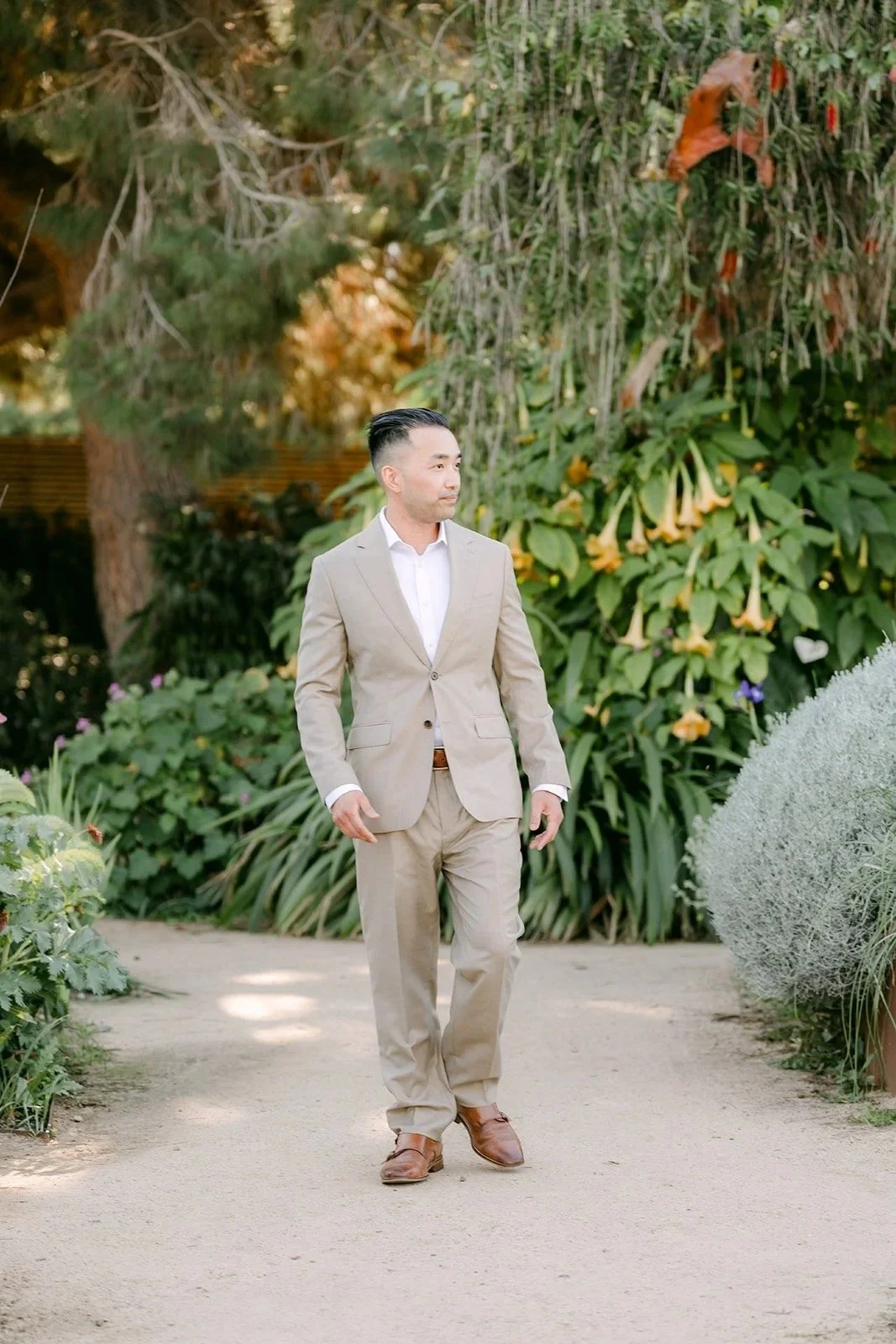 Vincent in a light tan suit walking down the garden path.