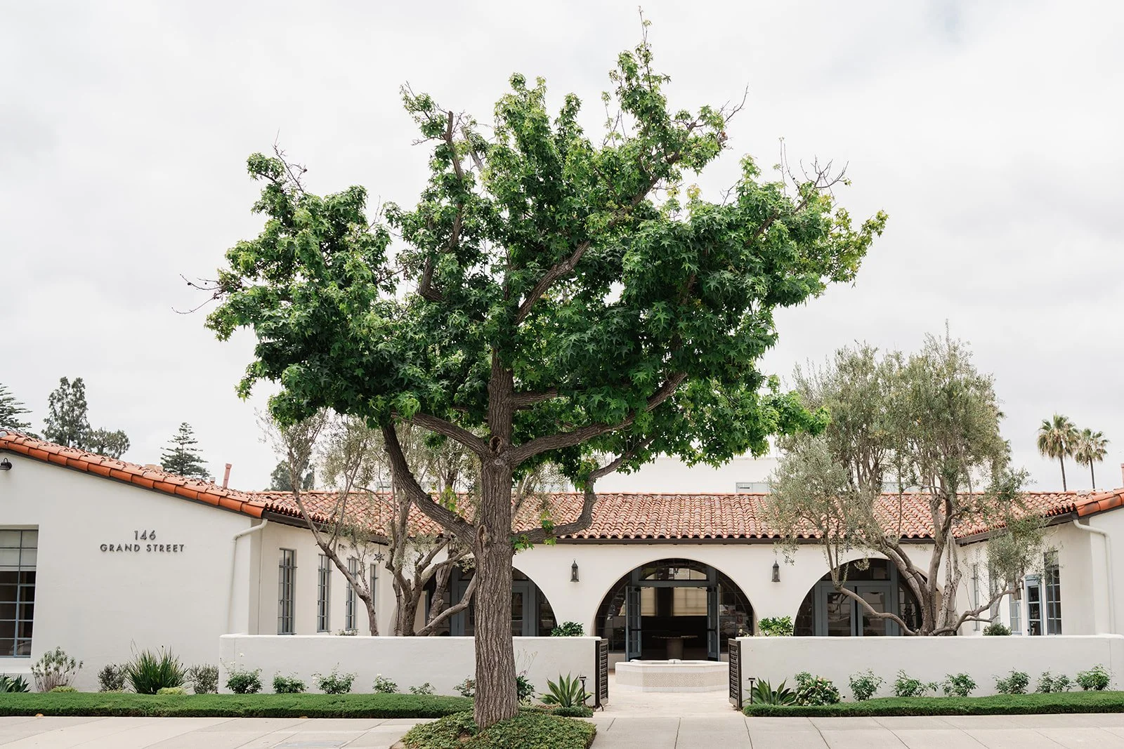 Grand Gimeno's Spanish style building with tile roof and trees in Orange