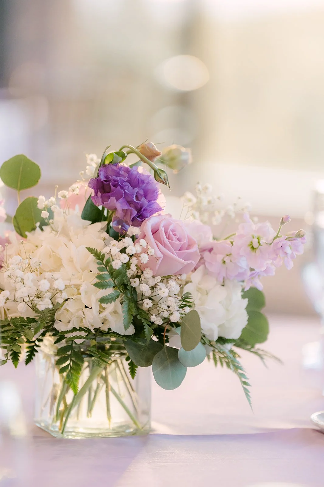 A small arrangement of lilac and white flowers on a reception table.